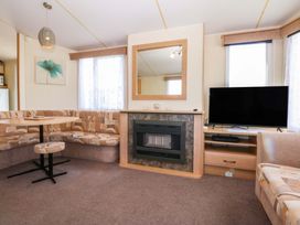 A living room with a table and seating area at Hideaway Lodge Abergele