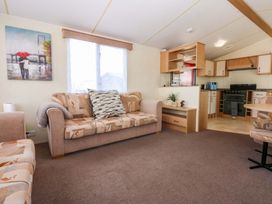 A living room with a sofa and kitchen area at Hideaway Lodge in Abergele