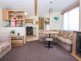 A living room with a sofa and dining table at Hideaway Lodge in Abergele