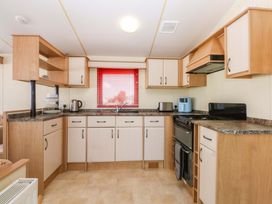 A kitchen featuring cabinets, a sink, stove, and appliances at Hideaway Lodge in Abergele