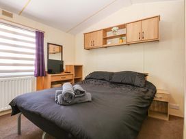 A bedroom with a bed, television, and storage at Hideaway Lodge in Abergele