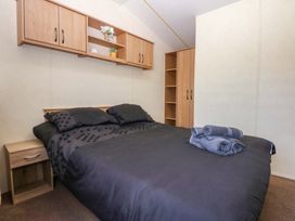 A bedroom with a bed and nightstand at Hideaway Lodge in Abergele