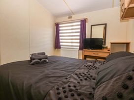 A bedroom with a bed and a TV at Hideaway Lodge in Abergele