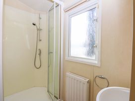 A bathroom with a shower and a window at Hideaway Lodge in Abergele
