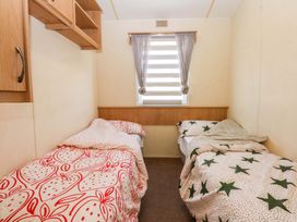 A bedroom with two beds and shelves at Hideaway Lodge in Abergele