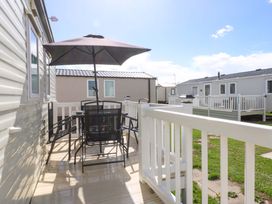 An outdoor seating area with a table and chairs at Hideaway Lodge in Abergele