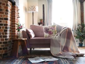 A living room with a sofa and flowers on a table at The Old Post Box 