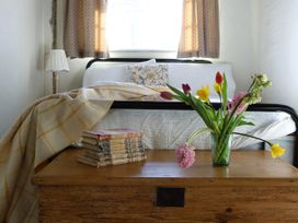 A bedroom with a bed, lamp, and flowers on a table at The Old Post Box