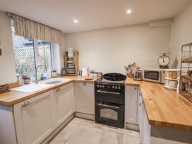 A kitchen with a stove, microwave, and sink at The Old Post Box in Halesworth