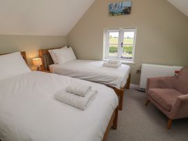 A bedroom with two beds, a lamp, and a window at 6 Gravel Hill in King's Lynn