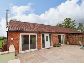 An exterior view of a brick building with a patio at The Owl Barn Cottage