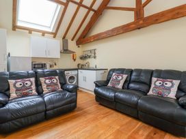 A living room with a sofa and kitchen area at The Owl Barn Cottage