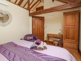 A bedroom with a bed, mirror, chair, table and wardrobe at The Owl Barn Cottage 