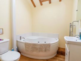 A bathroom with a bath tub, toilet, and wash basin at The Owl Barn Cottage 