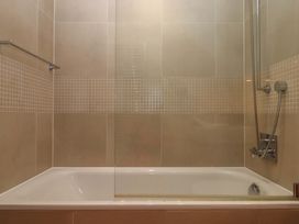 A bathroom with a bathtub and shower facilities at 26 Dart Marina