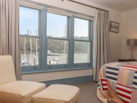 A bedroom with a view of boats through windows at 26 Dart Marina