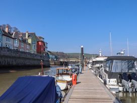 A dock with boats and houses along the waterfront at 26 Dart Marina
