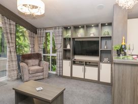 A living room with a chair and television at Feather Hill Lodge in Windermere