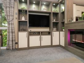 A living room with a television and shelves at Feather Hill Lodge in Windermere