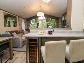 A living room with a sofa and dining area at Feather Hill Lodge in Windermere