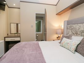 A bedroom with a bed and a mirror at Feather Hill Lodge in Windermere