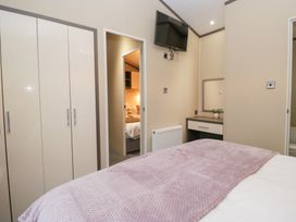 A bedroom with a wardrobe and a television at Feather Hill Lodge in Windermere