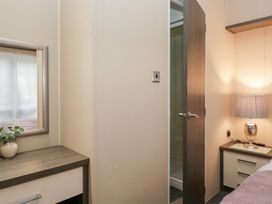 A bedroom with a mirror and a lamp at Feather Hill Lodge in Windermere