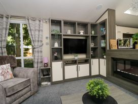 A living room with a television and furniture at Feather Hill Lodge White Cross Bay near Troutbeck Bridge