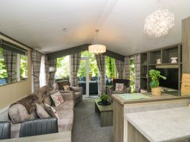 A living room with sofas, a coffee table, and a television stand at Feather Hill Lodge White Cross Bay near Troutbeck Bridge