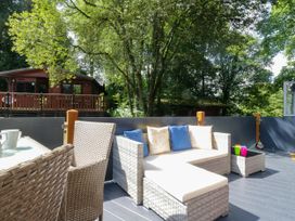 An outdoor patio with seating and a log cabin in the background at Feather Hill Lodge White Cross Bay, Skiptory Howe 38 near Troutbeck Bridge