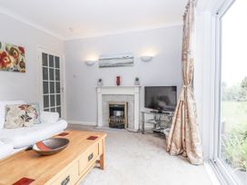 A living room with a sofa, coffee table, and television at Mayflower View in Dawlish
