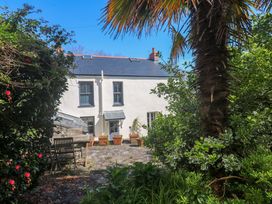 A garden with a dining table and palm tree at Pedn Brose Near Mousehole