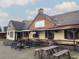 An outdoor seating area with tables and barrels at Rusty Barn in Limavady