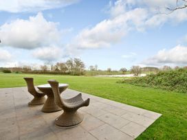 An outdoor area with a table and chairs overlooking a lake at Brayton in Aspatria