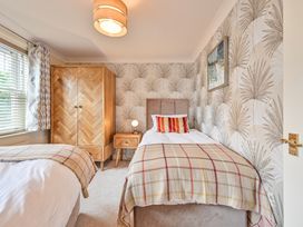 A bedroom with two beds and a wardrobe at Lisburne Place in Torquay