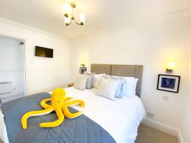 A bedroom with a bed, lamp, television and octopus plush toy at The Degas Sea View Suite in Torquay