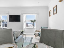 A living room with a television and windows at The Renior Sea View Suite in Torquay