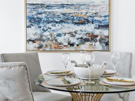A dining room with a round table set with glassware and artwork at The Renior Sea View Suite in Torquay
