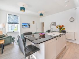 A kitchen with a sink, sofa, and television at The Falstone Apartment in Torquay