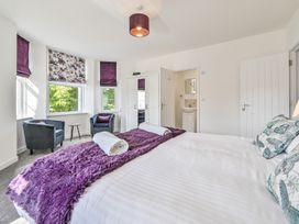 A bedroom with a bed, armchair, and bathroom access at The Falstone Apartment in Torquay