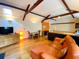 A living room with a television and dining area at Upper Stable - The Stables Apartments at Meadfoot Bay, Torquay