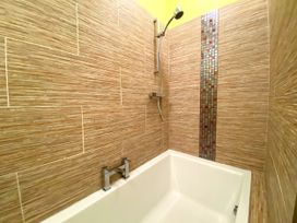 A bathroom with a bathtub and shower at Upper Stable - The Stables Apartments at Meadfoot Bay, Torquay