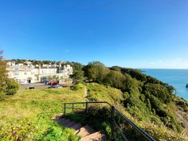 An outdoor area with a building next to the sea at Upper Stable - The Stables Apartments at Meadfoot Bay, Torquay