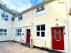 An outdoor view of Stable Cottage with red doors and planters at Lower Stable - The Stables Apartments at Meadfoot Bay in Torquay