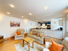 A living room with sofas and a kitchen area at Lower Stable - The Stables Apartments at Meadfoot Bay in Torquay
