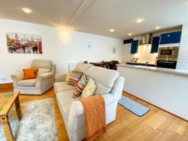 A living room with a sofa and kitchen area at Lower Stable - The Stables Apartments at Meadfoot Bay in Torquay