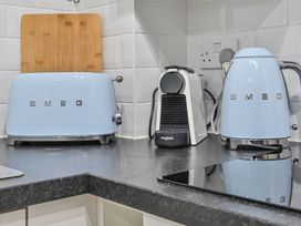 A kitchen with a toaster, kettle, coffee machine, and chopping board at Muntham Deluxe Apartment 2 in Torquay