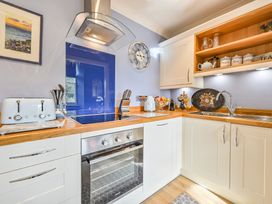 A kitchen with a cooker, sink, and wall clock at Muntham Apartment 4 in Torquay