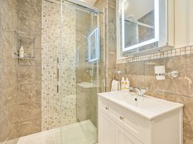A bathroom with a shower, vanity, and mirror at Muntham Apartment 4 in Torquay