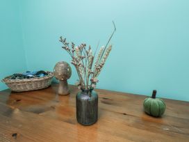 A table with dried flowers in a vase and decorative items at Starlight Cottage